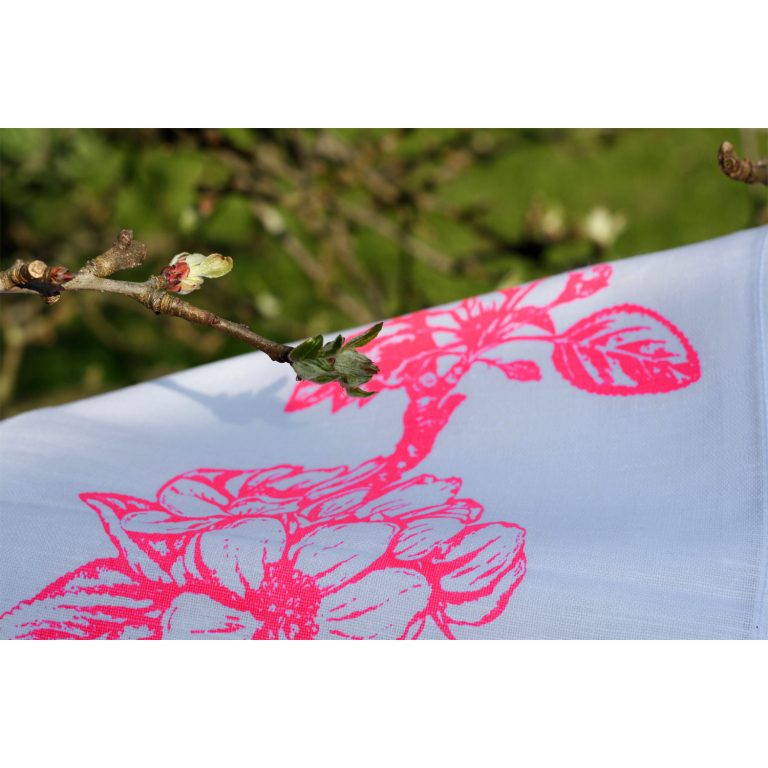 Frohstoff Nahaufnahme eines Geschirrtuchs mit Apfelblüten Motivs in neonpink in einem blühenden Baum hängend