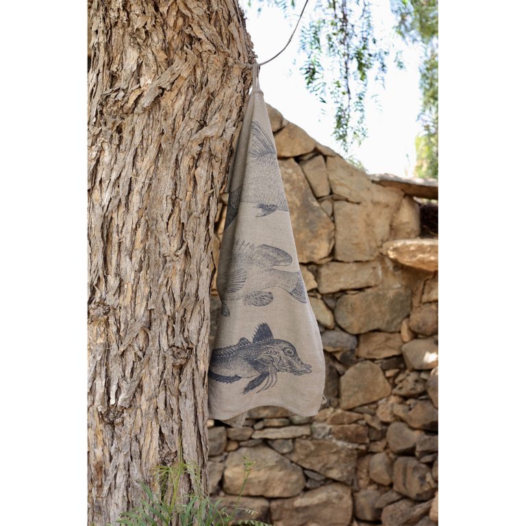 Frohstoff Geschirrtuch aus Leinen mit Fischtrio Motiv an einem alten Baum aufgehängt vor einer Natursteinwand