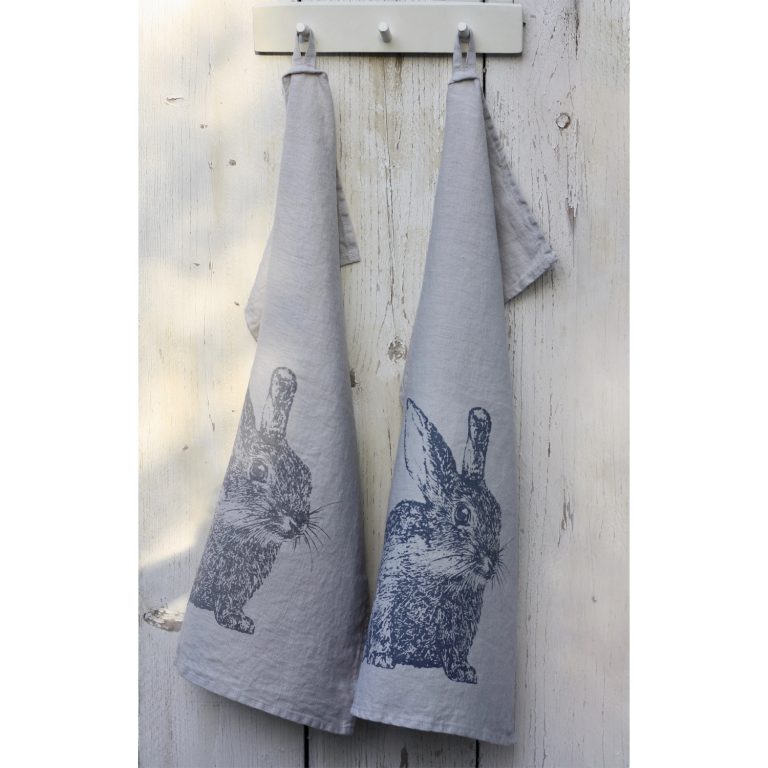 Frohstoff zwei Geschirrtücher aus Leinen Grau mit Wildkaninchen Motiv an einer weißen Holzwand aufgehangen