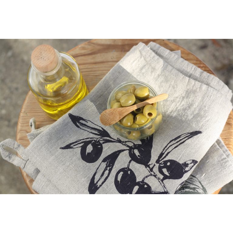 Frohstoff Geschirrtuch aus Leinen mit Olive Motiv dekoriert mit einer Schale gefüllt mit Oliven und daneben eine Flasche mit Olivenöl darunter ein hölzender Hocker