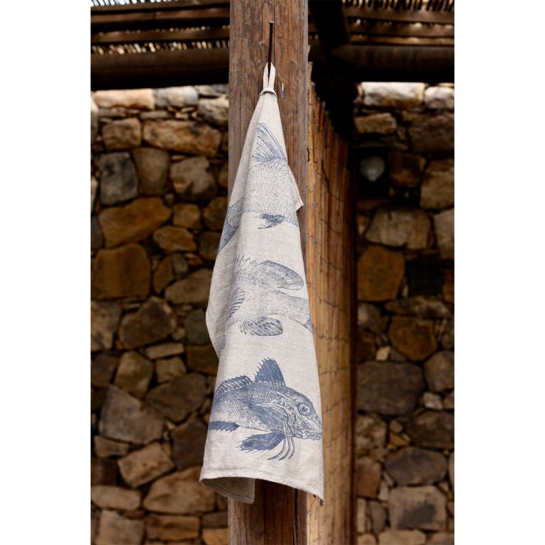 Frohstoff Geschirrtuch aus Leinen mit Fischtrio Motiv an einem Holzbalken aufgehängt eine Steinwand im Hintergrund