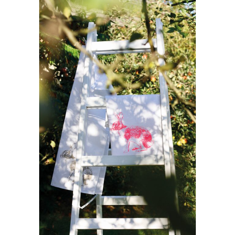 Frohstoff Geschirrtuch mit Hasen Motiv in neonpink über eine weiße Leiter gelegt die in der Natur steht