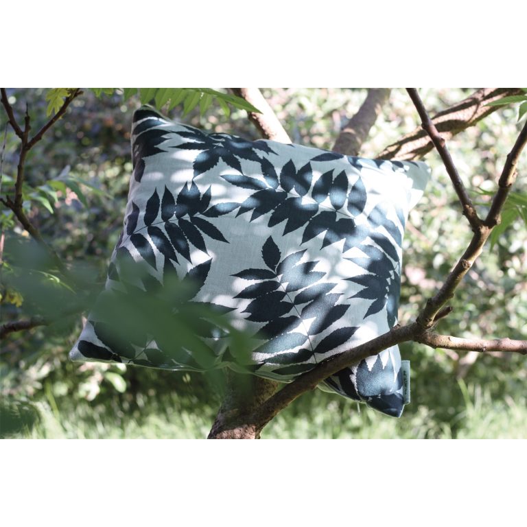 Frohstoff Kissen aus Leinen Grau mit Essigbaum Motiv in die Äste eines Baumes gelegt