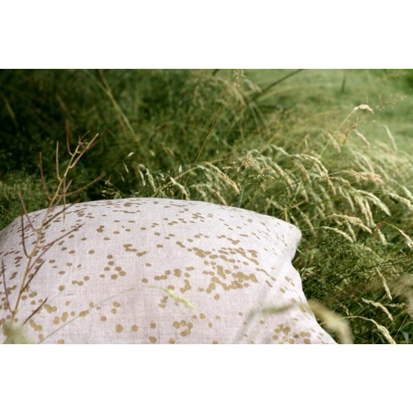 Frohstoff Kissen aus Leinen mit Blüten Motiv in Messing in hohem Gras liegend