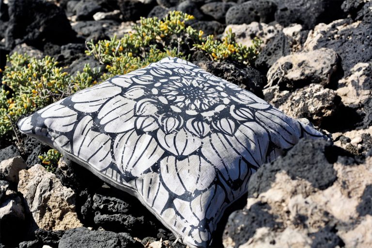 Frohstoff Kissen aus Leinen Natur mit Dahlie Motiv zwischen Salzwasserküstensteinen liegend