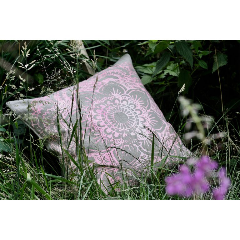 Frohstoff Kissen aus Leinen mit Ornament Motiv in pink. Das Kissen liegt in hohen Gras