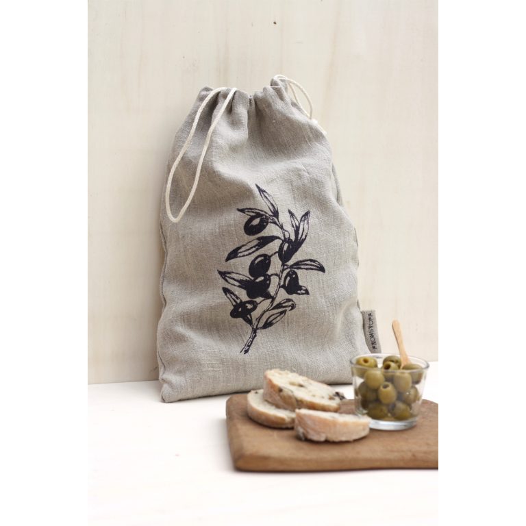 Frohstoff Leinenbeutel mit Oliven Motiv davor ein Holzbrett mit Brot und einer Schale mit Oliven