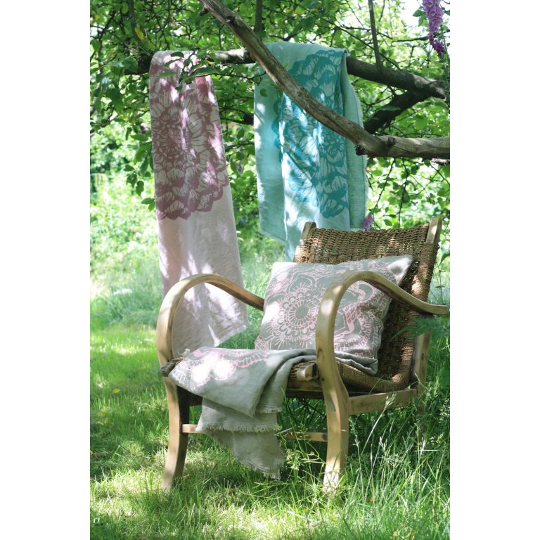 Frohstoff mehrere Plaids aus Leinen Rosa und Minze mit Ornament Motiv in einem Baum gelegt ein Leinenkissen und Plaid auf einem Stuhl unter dem Baum