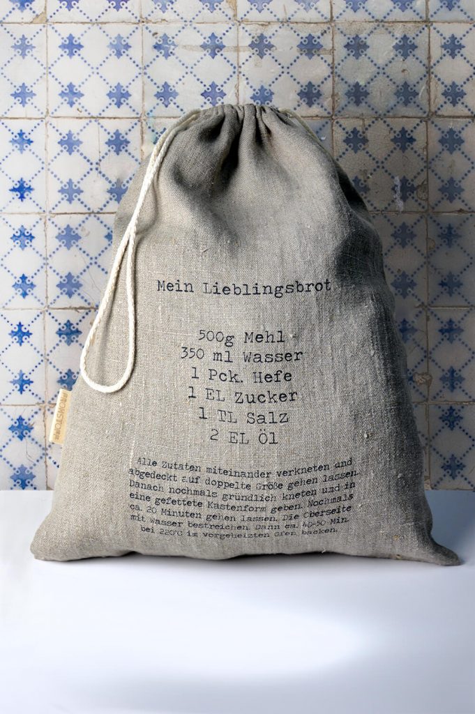 Frohstoff Brotbeutel aus Leinen mit Rezept Motiv für "Mein Lieblingsbrot" vor einer blau-weiß gefliesten Wand