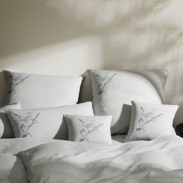 Frohstoff Verschiedene Kissen großen mit Spatz-Motiv im Farbton blaugrau in einem Bett angerichtet