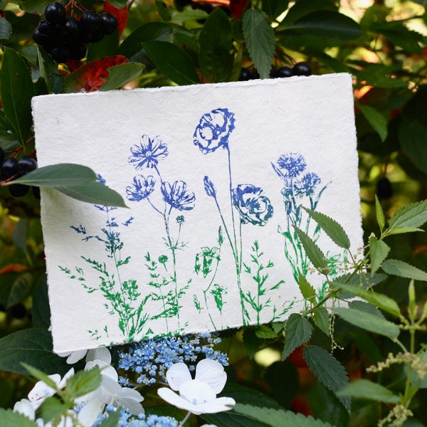 Frohstoff Kunstdruck mit Wildblumen-Motiv in Blau-Grün in einen Busch mit Beeren und Blumen gelegt